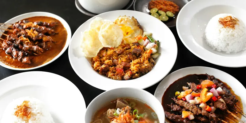 Sate, soto, dan nasi lauk khas Indonesia di atas meja